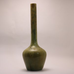 May include: A tall, slender green ceramic vase with a bulbous base. The vase has a mottled, textured surface with shades of green and brown.