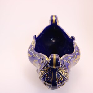 Puede incluir: Un cuenco de cer&aacute;mica azul y dorado con intrincados dise&ntilde;os florales y de dragones. El cuenco est&aacute; vac&iacute;o y tiene una boca ancha y abierta.