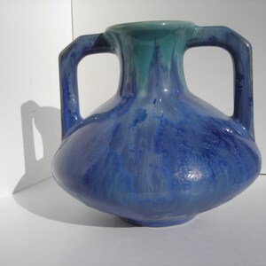 May include: A blue and green glazed ceramic vase with two handles. The vase has a rounded body and a narrow neck.