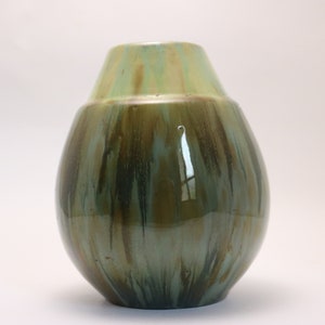 May include: A green ceramic vase with a rounded body and a slightly flared opening. The vase has a streaky glaze with shades of green, brown, and blue.