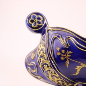 Puede incluir: Un cuenco de cer&aacute;mica azul y dorado con un dise&ntilde;o floral. El cuenco tiene un borde festoneado y un asa decorativa.