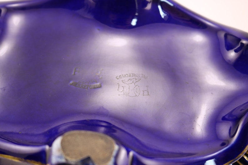 Puede incluir: Un cuenco de cer&aacute;mica azul con un borde dorado y una marca de fabricante en la parte inferior. La marca incluye el texto "PIECE DEPOSE" y un p&aacute;jaro estilizado.