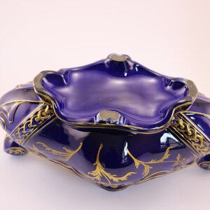 Puede incluir: Un cuenco de cer&aacute;mica azul cobalto con detalles dorados y un dise&ntilde;o decorativo. El cuenco tiene un borde festoneado y una forma ligeramente redondeada.