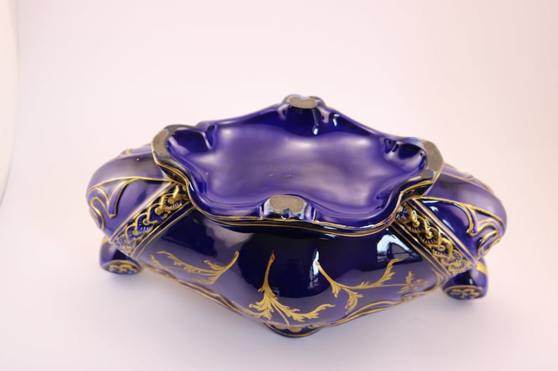 Puede incluir: Un cuenco de cer&aacute;mica azul cobalto con detalles dorados y un dise&ntilde;o decorativo. El cuenco tiene un borde festoneado y una forma ligeramente redondeada.