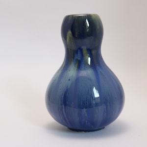 May include: A blue and green ceramic vase with a rounded, bulbous shape. The vase has a glossy finish and a unique, abstract pattern.