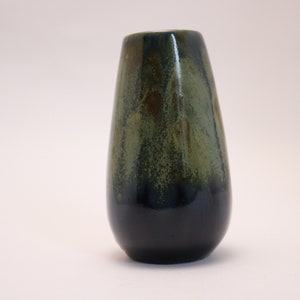 May include: A small, dark green and black ceramic vase with a rounded, teardrop shape.