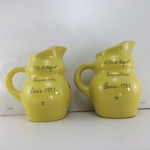 May include: Two yellow ceramic pitchers with a design of green leaves and the text "Côte d'Azur Exposition Paris - 1937."