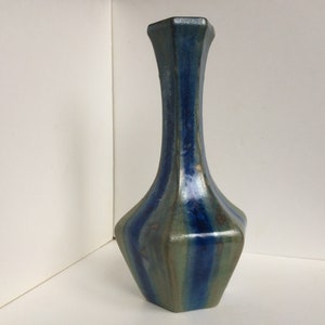 May include: A blue and green ceramic vase with a geometric shape and a narrow neck.