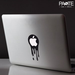 Può includere: Un adesivo bianco e nero di un logo di mela che cola su un laptop argentato.