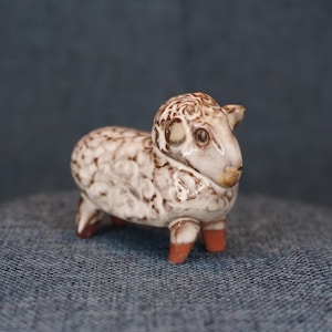 May include: A set of three ceramic mugs with a speckled, matte finish. The mugs are in shades of cream, light gray, and dark gray. Each mug has a simple, minimalist design and a rounded handle.