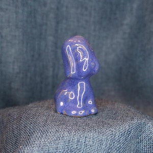 May include: A small, blue ceramic figurine of a dog. The figurine has white glaze accents and a textured surface.