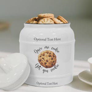 Op de afbeelding: Witte keramische koekjespot met een zwarte rand, gevuld met koekjes. De pot heeft de tekst "Optional Text Here" bovenaan en onderaan, en "Gave me cookie, Got you cookie" met een chocolade chip cookie afbeelding in het midden.