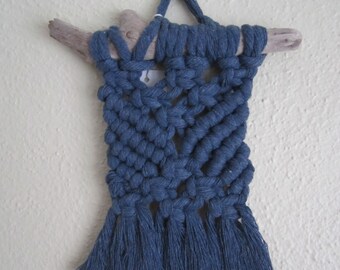 May include: A blue macrame wall hanging with a driftwood branch at the top and tassels at the bottom.