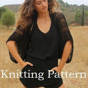 May include: A black crochet shrug with a loose, open weave. The shrug has a short, cropped length and wide, flowing sleeves. The model is wearing the shrug over a black tank top and black shorts.