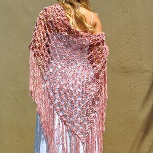 May include: A pink and white crochet shawl with fringe. The shawl is made of a lightweight yarn and has a delicate, openwork design.