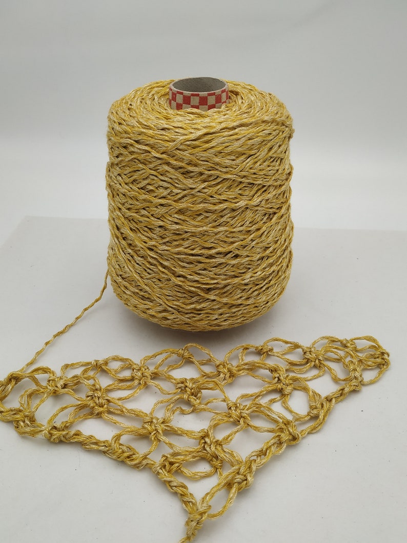 May include: A spool of gold yarn with a crocheted piece made from the yarn. The yarn has a shimmery, textured look.