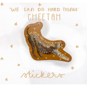 May include: A brown cheetah sticker with the text "WE CAN DO HARD THINGS" and the word "CHEETAH" in a handwritten font. The cheetah is in a leaping pose with its mouth open. The sticker is on a white background with small gold stars.