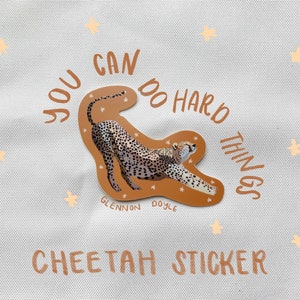 May include: A brown cheetah sticker with the text "You can do hard things" in a circle around the cheetah. The sticker also includes the text "Glennon Doyle" and "Cheetah Sticker".