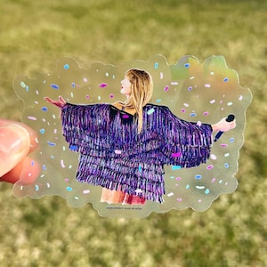 May include: A clear sticker with a colourful confetti background featuring a woman wearing a sequined purple and black jacket, holding a microphone and singing. The text "september sun studio" is at the bottom of the sticker.