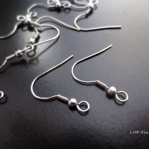 May include: Silver earring hooks with a small ball at the end. The hooks are made of metal and are designed for attaching earrings.