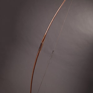 May include: A wooden bow with a string attached. The bow is brown and has a natural wood finish. The string is black and is tied to the ends of the bow.