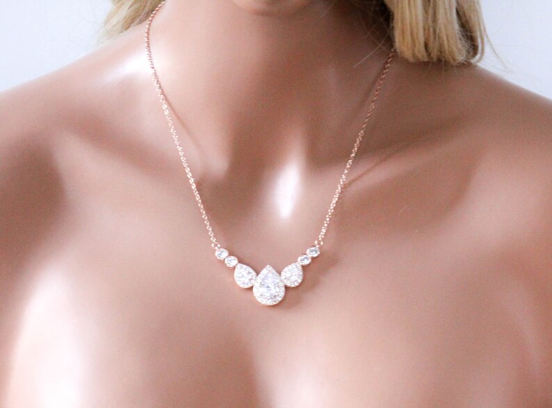 Pu&ograve; includere: Una collana in oro rosa con un ciondolo a forma di lacrima incastonato con pietre di zircone cubico trasparenti.
