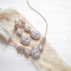 Pu&ograve; includere: Un set di collana e orecchini in oro rosa con cristalli a forma di goccia e cristalli rotondi pi&ugrave; piccoli.