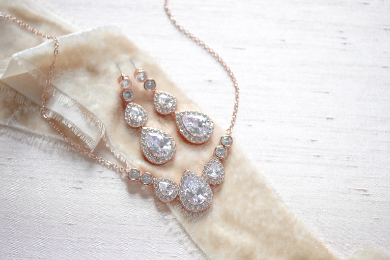 Pu&ograve; includere: Un set di collana e orecchini in oro rosa con cristalli a forma di goccia e cristalli rotondi pi&ugrave; piccoli.