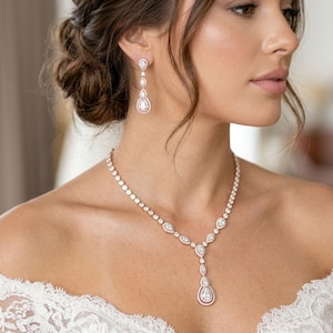 Bride wearing a rose gold cubic zirconia bridal necklace and matching drop earrings with an off-the-shoulder lace wedding gown from Exquisite Bride Shop.