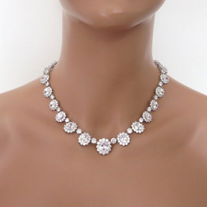 May include: A silver necklace with a row of large, clear, round rhinestones set in a flower-like design.