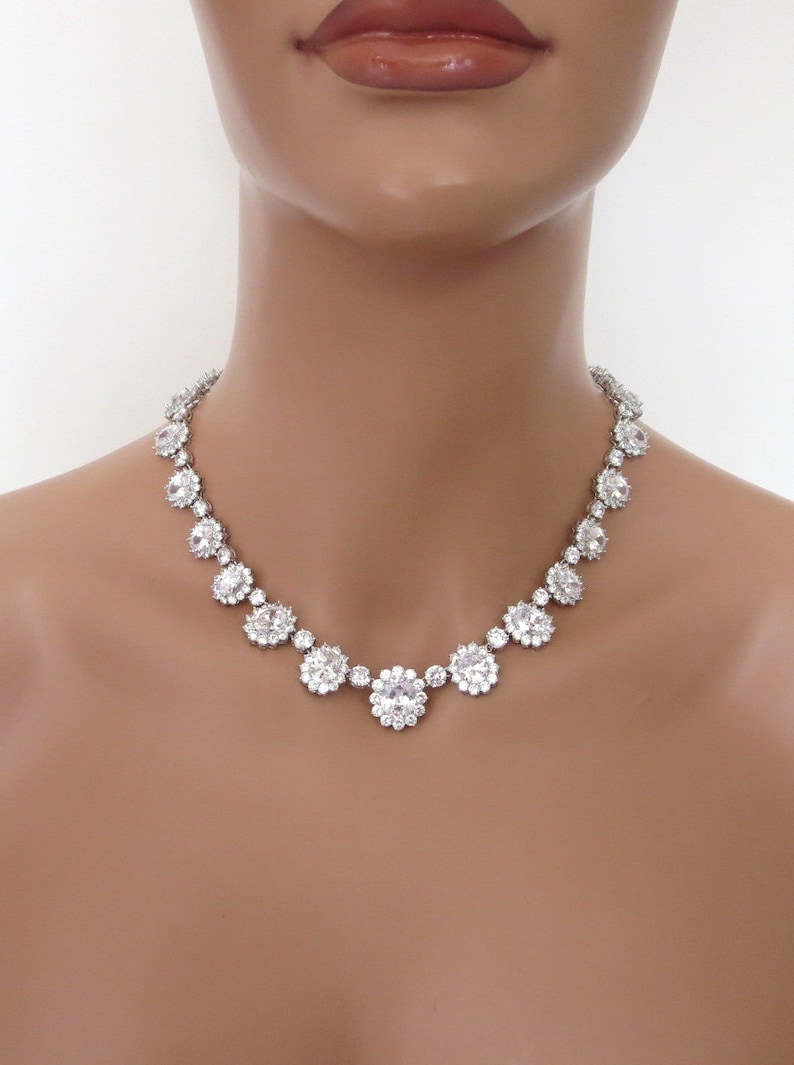 May include: A silver necklace with a row of large, clear, round rhinestones set in a flower-like design.