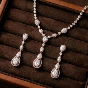 Rose gold cubic zirconia bridal necklace and matching drop earrings displayed on a luxury brown jewelry tray for bridal jewelry.