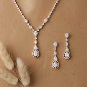 Rose gold cubic zirconia bridal necklace and matching drop earrings displayed on a neutral background for timeless bridal elegance.