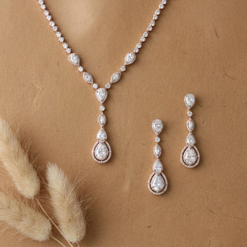 Rose gold cubic zirconia bridal necklace and matching drop earrings displayed on a neutral background for timeless bridal elegance.