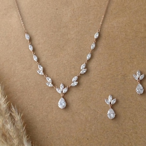 Rose gold bridal necklace and earrings set with marquise cubic zirconia leaves and pear-shaped CZ drops displayed on a neutral background for the Exquisite Bride.