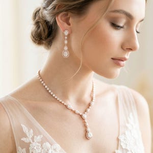 Bride wearing an elegant rose gold cubic zirconia bridal necklace and matching drop earrings with a soft tulle wedding gown.