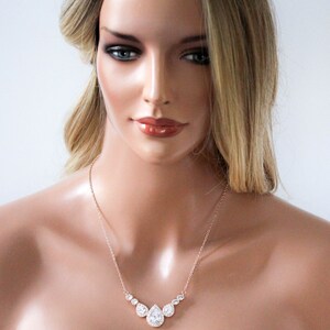 Pu&ograve; includere: Una collana in oro rosa con un ciondolo a forma di lacrima e pietre rotonde pi&ugrave; piccole. La collana &egrave; su un manichino con i capelli biondi.