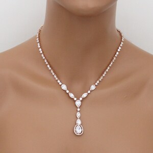 May include: A rose gold necklace with a teardrop pendant. The necklace is made of cubic zirconia stones and has a delicate design.