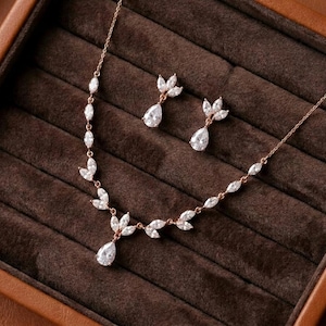 Rose gold bridal necklace and earrings set featuring cubic zirconia marquise leaves with pear-shaped CZ drops displayed in a luxury jewelry box for the Exquisite Bride.