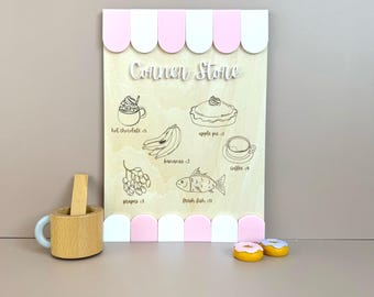 May include: A wooden sign with a pink and white awning that says "Conner Stone" and lists various food items with prices, including hot chocolate, apple pie, bananas, coffee, grapes, and fresh fish.