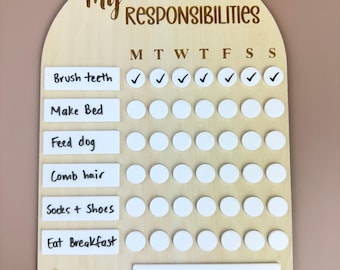 May include: A wooden chart with a white arch shape and the text "My Responsibilities" at the top. The chart has a list of daily chores with checkboxes for each day of the week. The chores include "Brush teeth", "Make Bed", "Feed dog", "Comb hair", "Socks & Shoes", and "Eat Breakfast". The chart also has a reward section with the text "REWARD £10 Pocket Money".