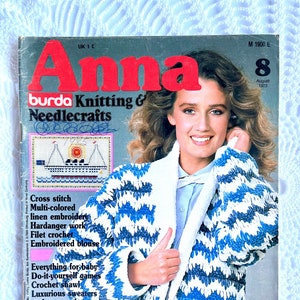 May include: The cover of "Anna" magazine features a smiling woman wearing a blue and white crochet jacket. The magazine cover includes text such as "Burda Knitting & Needlecrafts" and "Super crochet jacket". The August 1983 issue also features cross stitch and embroidery.