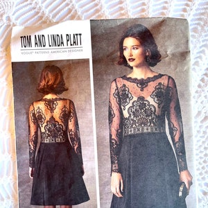 May include: A black and white sewing pattern for a dress with a lace overlay. The pattern is from Vogue Patterns and designed by Tom and Linda Platt. The pattern number is V1428.