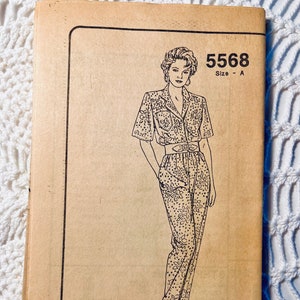 May include: A vintage sewing pattern envelope with a black and white illustration of a woman wearing a jumpsuit with a floral print. The pattern number is 5568 and the size is A.