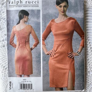 May include: A sewing pattern by Ralph Rucci for a fitted dress with long sleeves and a side slit. The pattern features two views of the dress in a peach-colored fabric. The pattern number is V1458, and the size range is 4-6-8-10-12.