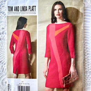 Peut inclure: Un patron de couture de Tom et Linda Platt pour une robe. Le patron présente une robe rouge avec un motif de blocs de couleurs dans les tons de rouge et d'orange. Le patron comprend le texte "V1555" et "A5".