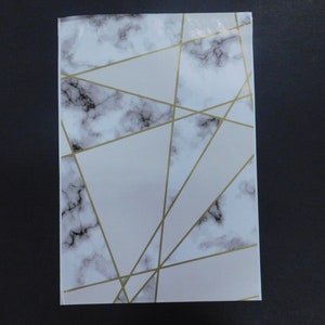 May include: A white notebook cover with a marble pattern and gold geometric lines.