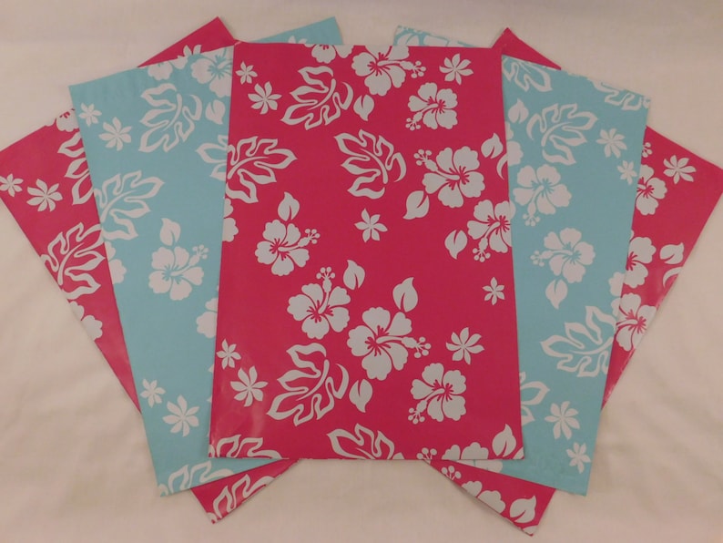 May include: Four sheets of wrapping paper with a tropical floral pattern. The paper is pink with white hibiscus flowers and leaves. The back of the paper is light blue with white hibiscus flowers and leaves.