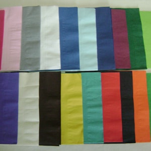 May include: Assortment of 20 solid color paper napkins. The napkins are arranged in two rows of ten. The colors are: pink, gray, white, blue, light blue, dark blue, burgundy, green, lime green, purple, white, black, yellow, teal, red, black, orange, green.