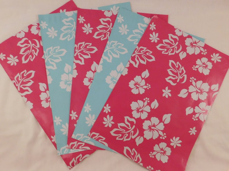 May include: Five sheets of wrapping paper with a tropical floral design. The paper is pink with white hibiscus flowers and leaves. Two sheets are light blue with white hibiscus flowers and leaves.